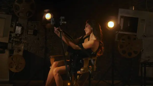 映画と映画の舞台裏広告クリエイティブコンセプト 黒いドレスのブルネット女性 監督の椅子の裸足に座って レトロビデオカメラを保持し 自分自身を記録し — ストック写真