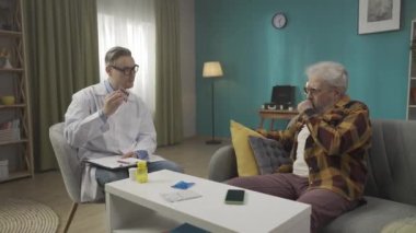 Hastanın evdeki durumunu kontrol eden bir doktorun tam boy videosu. Sağlık sorunları olan yaşlı bir adama reçete yazıyor. Sağlık sistemi, sağlık hizmeti, reklam. HDR