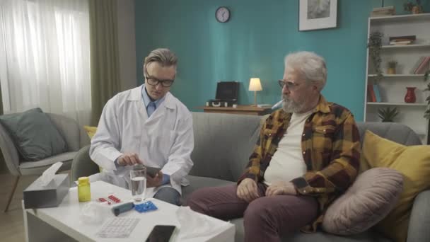 一个医生在家中检查病人病情的全片录像 他正在使用一种药片和处方药 一种给一个有健康问题的老年人的药物 医疗服务 — 图库视频影像