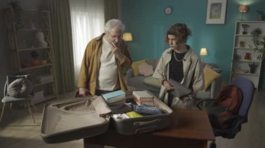 Eşyalarını bavula koyan bir gencin videosu. Dedesi süveter alması için ısrar ediyor ama torunu reddediyor. Üniversite, üniversite, yeni bir yere taşınmak. HDR BT2020