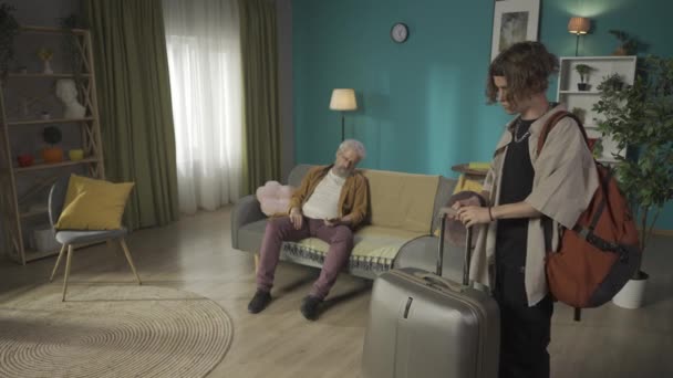 10代の若い男の魔女のスーツケースのビデオは または休暇から家に帰って 彼の眠っている祖父を見て 彼を起きて暖かく迎えました レユニオン 家族の価値 — ストック動画