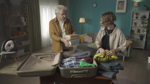 ティーンエイジャーのビデオ 彼の祖父 祖父とスーツケースに自分の持ち物を詰め込む若い男 少年は急いで誰かにテキストを送っているが 遅刻するのを躊躇している 新しい場所に移動する — ストック動画