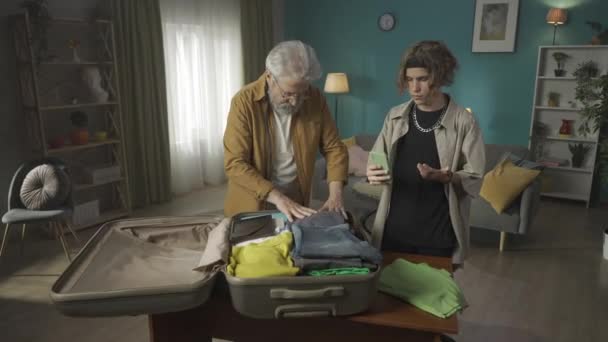 ティーンエイジャーのビデオ ビデオを作る 彼の旅について生きる 祖父が荷物をスーツケースに詰め込んでいる間 新しい場所に引っ越して — ストック動画
