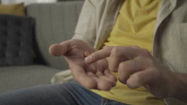 Yakın plan, koltukta oturan orta yaşlı bir adamın avuç içi görüntüsü. İlaçları gösteriyor, elinde ilaç var ve parmaklarıyla dokunuyor. Sağlık, eczane, ilaç reklamları.