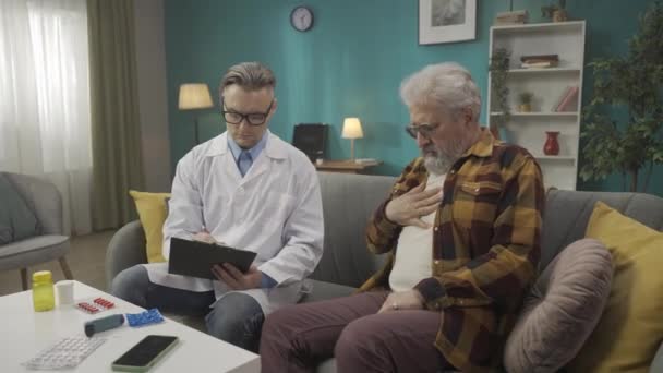 自宅で患者の状態をチェックする医師のフルサイズのビデオ 彼は老人が描いた症状を書き留めている 医療システム 医療サービス Hdr Bt2020について — ストック動画