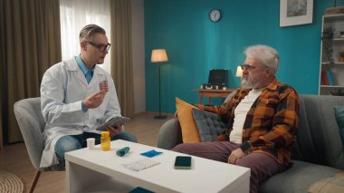 Hastanın evdeki durumunu kontrol eden bir doktorun tam boy fotoğrafı. Sağlık sorunları olan yaşlı bir adama reçete yazıyor. Sağlık sistemi, sağlık hizmetleri, reklam.