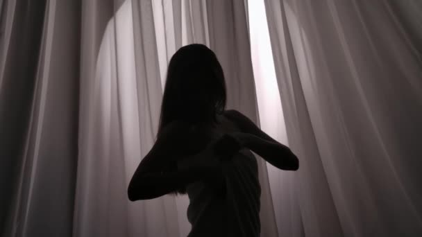 一名年轻女子刚从淋浴间出来的中等慢镜头 她从身体上拿开毛巾 在柔和的灯光下背对着窗帘 产品广告 自我照顾 — 图库视频影像