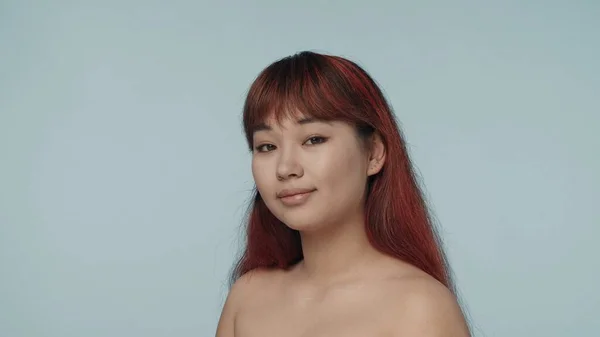 一个有着红色染发和裸体妆容的年轻的神童女子 站在半圆形的特写镜头前 看着相机 微笑着 化妆品 护肤广告 — 图库照片