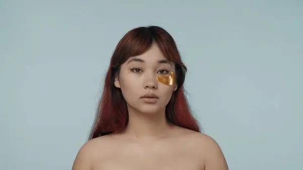 一个有着红色染发和裸体妆容的年轻女子在一只眼皮底下戴着金色眼罩的特写照片 黑眼圈美容 化妆品 护肤广告 — 图库照片