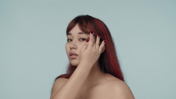 赤い染められた髪とヌードのメイクを施した若いセミナーの女性のクローズアップされたスローモーションビデオは 彼女の顔 体を横切って手を動かしました ビューティー スキンケア広告 — ストック動画