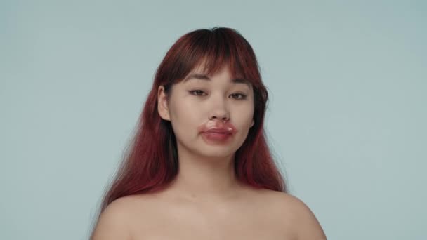 一个有着红色染发和裸体妆容的年轻女性 戴着唇膏 触摸着她的脸 干裂的嘴唇美容 化妆品 护肤广告 — 图库视频影像