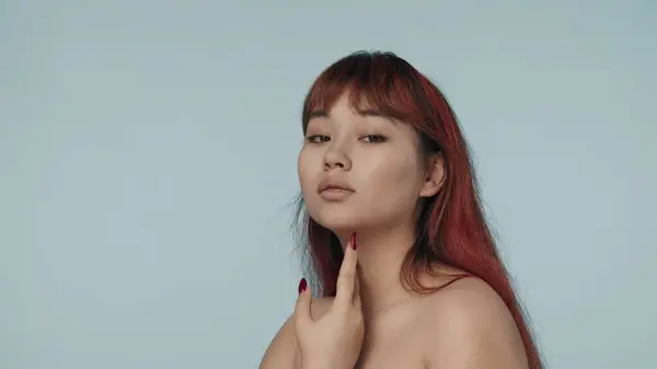 一个有着红色染发和裸体妆容的年轻的神童女子的近照被孤立地拍照 她把手放在脖子上 转身看着相机 化妆品 护肤广告 — 图库照片