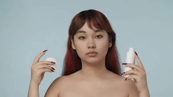一个有着红色染发的年轻女子的近照 她拿着卸妆剂和棉垫 把眼影从眼睑上移开 化妆品 护肤广告 — 图库照片