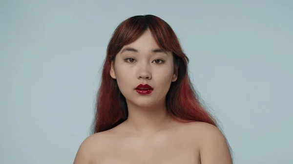 一个有着红色染发和裸体妆容的年轻女性 穿着鲜红色口红 直视着相机的特写照片 化妆品 护肤广告 — 图库照片