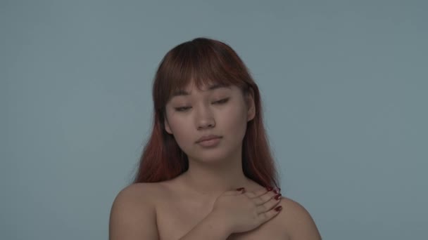 一个有着红色染发和裸体妆容的年轻的神童女子凝视着相机 在她的身体上涂上护肤霜的特写镜头 这是一个孤立的慢动作视频 护肤广告 — 图库视频影像