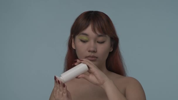 一个有着红色染发和裸体化妆的年轻女性用棉垫和溶液去除眼睑上的化妆品的特写视频 美容美发化妆品广告 — 图库视频影像