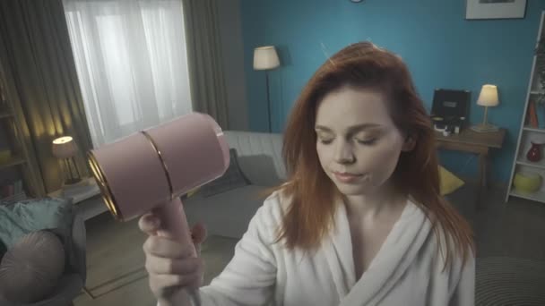 Gadis Muda Berdiri Sebuah Ruangan Memegang Pengering Rambut Melihatnya Dengan — Stok Video