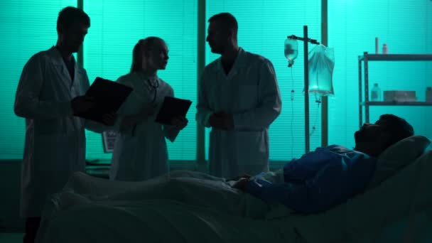 Pełnowymiarowy Filmik Trzema Lekarzami Stojącymi Wokół Pacjenta Leżącego Szpitalnym Łóżku — Wideo stockowe