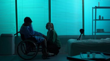 Engelli bir adamın tam boy silueti, tekerlekli sandalyede hareket kabiliyeti zayıf bir hasta, umutsuzluk içinde ağlıyor ve sevdiği genç kadının yanında inkar ediyor. Hastane, rehabilitasyon, sağlık..