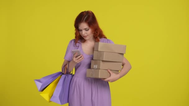Νεαρή Γυναίκα Τσάντες Για Ψώνια Και Χάρτινα Κουτιά Χρησιμοποιεί Smartphone — Αρχείο Βίντεο