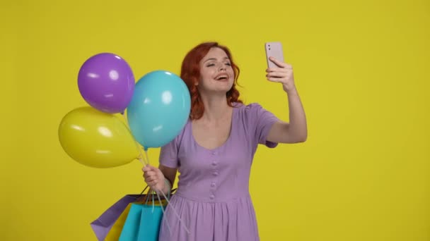 Κοκκινομάλλα Γυναίκα Τσάντες Ψώνια Και Πολύχρωμα Μπαλόνια Παίρνει Μια Selfie — Αρχείο Βίντεο