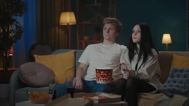 最初の愛と関係創造的なコンセプト 十代のカップルの肖像画 ソファーに座ってポップコーンを食べ 映画を見ている少年と少女 少年は少女を抱きしめようとするが 彼女は断る — ストック動画