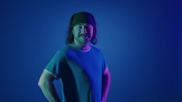 Saçında Bantla Gülümseyen Uzun Saçlı Bir Adamın Portresi Stüdyoda Elini — Stok video