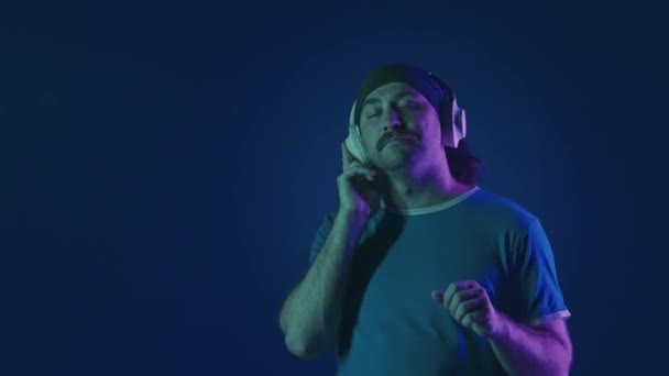 Muž Bílých Bezdrátových Sluchátkách Poslouchá Hudbu Tance Muž Ateliéru Modrém — Stock video
