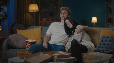 İlk ilişkiler yaratıcı konsept. Boş zamanlarını geçiren genç bir çiftin portresi. Oğlan ve kız kanepede oturup patlamış mısır yiyor ve film izliyor. Oğlan kıza sarılıyor..