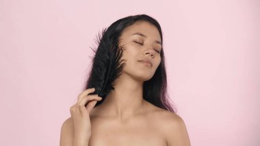 Güzellik ve cilt bakımı yaratıcı bir kavram. Çekici genç modelin yakın çekim stüdyo çekimi. Uzun saçlı, siyah tüylü ve yüzüne dokunan güzel Asyalı kız..