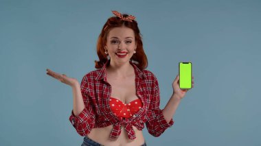 Mavi arka planda parlak makyajlı genç bir kadın var. Kameraya bakıyor ve elinde yeşil ekranlı bir telefon tutuyor. Şaşırdığını gösterir, Joy. İşte reklamınız, ürününüz. HDR