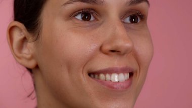 Deri dokusu ve güzellik konsepti. Esmer kadın portresi. Açık gözlü, doğal yumuşak tenli ve makyajsız, dişleri açık gülümseyen güzel beyaz bir kızın yakın çekimi..