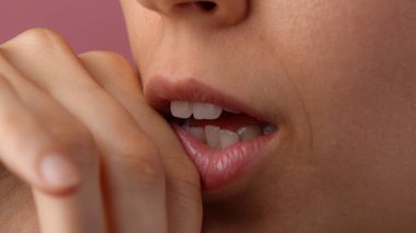 Deri dokusu ve güzellik konsepti. Çekici kadın modelin portresi. Kafkasyalı genç bir kızın yakın çekimde ağzı açık, yüzünün bir kısmı makyajsız, parmaklarıyla dudaklarına dokunuyor..