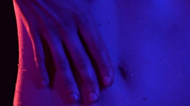 Deri dokusu ve vücut sağlığı konsepti. Genç kadın modelin portresi. Güzel beyaz kadın vücudunun neon ışıkta bir parçası, karın bölgesini tutarak duş aldıktan sonra tenine dokunuyor..