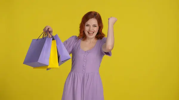 Young Redhaired Woman Holding Bright Shopping Bags Excitedly Making Victory — Stock Photo, Image