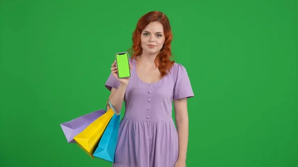 Kobieta Torbami Zakupy Trzyma Smartfona Zielonym Ekranem Młoda Kobieta Studiu — Zdjęcie stockowe