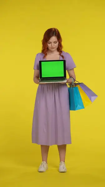 Рыжая Женщина Держит Ноутбук Зеленым Экраном Женщина Полный Рост Сумками — стоковое фото
