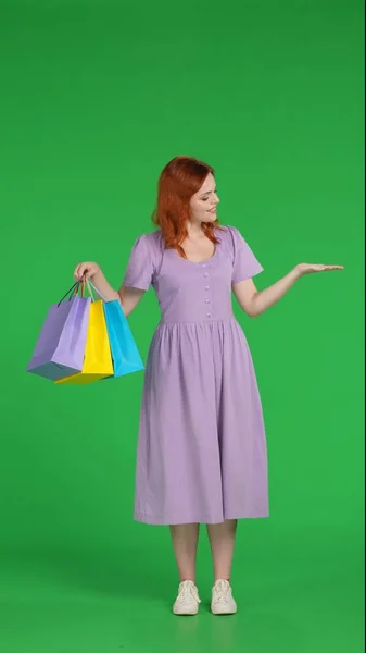 Redhaired Woman Shopping Bags Points Something Her Hand Full Length — Stock Photo, Image