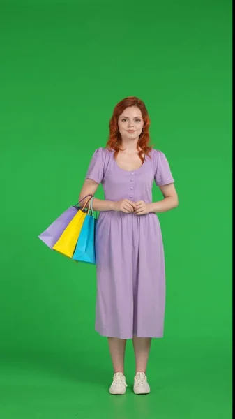 红头发的女孩拿着彩色购物袋 全长的女人在工作室的绿色屏幕上 垂直射击 黑色星期五 — 图库照片