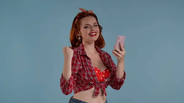 写真は青い背景に明るく色付けされたメイクをした若い赤毛の女性を示しています 彼女は携帯電話を持っているカメラを見つめている さらなる描写は そして幸福である Hdrについて — ストック写真