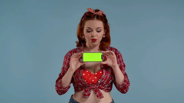 写真は青い背景にある若い女性を示しています 緑色の背景を持つ携帯電話を見て 彼女の前にそれを保持しています これがあなたの広告かもしれません 製品について 中型ショット Hdrについて — ストック写真