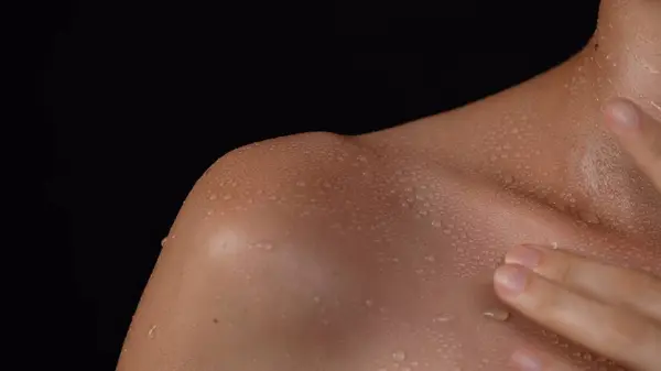 Skin texture and bodycare creative concept. Portrait of attractive model. Closeup shot of caucasian woman body part in studio light, collarbone area touching skin in water drops after bathing.