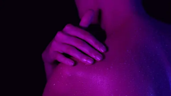 スキンテクスチャーとボディケア美容コンセプト クローズアップスタジオ 紫色のネオン ライトの若い女性の体部分のショット シャワーの後で肩に水滴で彼女の皮に触れる女性 — ストック写真
