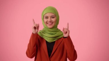 Orta ölçekli izole bir video, tesettür ve duvak takan çekici bir genç kadını çekiyor. Yukarıda bir şeyin altını çizerek parmaklarını havaya kaldırıyor. Reklamınız için yer, modellik, promosyon.