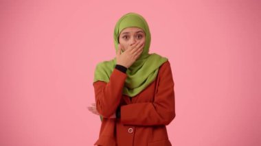 Orta ölçekli izole bir video, tesettür ve duvak takan çekici bir genç kadını çekiyor. Ağzını kapatarak şaşkınlık ve şok belirtileri gösteriyor. Reklamınıza, kültürünüze, çeşitliliğinize yer.