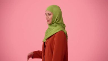 Orta profilli, tesettürlü, duvak takan çekici bir genç kadın görüntüsü. Sinsi görünüyor, ağzını kapatıyor, bir sır söylüyor. Reklamınıza, kültürünüze, çeşitliliğinize yer.