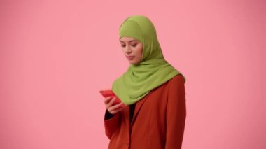 Orta ölçekli izole bir video, tesettür ve duvak takan çekici bir genç kadını çekiyor. O bir akıllı telefon tutuyor ve kameraya dolarları gösteriyor. Reklam, kültür ve çeşitliliğe yer.