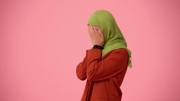 中規模の隔離されたビデオは ヒジャーブ ベールを身に着けている魅力的な若い女性をキャプチャします 彼女は両手で顔を覆い 頭を揺さぶっている 多様性のための場所 — ストック動画