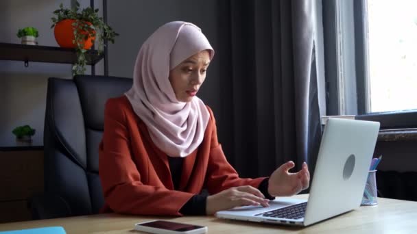 中等尺寸的视频拍摄了一个戴着头巾 头戴头巾的年轻貌美女子 她正在一台笔记本电脑上工作 不停地打字 好像她疯了似的 文化多样性 就业和教育 — 图库视频影像
