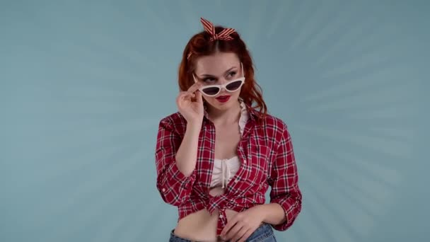 Kadrze Młoda Rudowłosa Kobieta Jasnym Makijażem Niebieskim Tle Podnosząc Okulary — Wideo stockowe